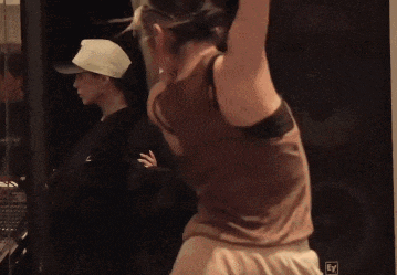 a woman in a brown tank top is dancing in a room