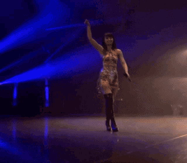 a woman in a dress is dancing on a stage with a microphone