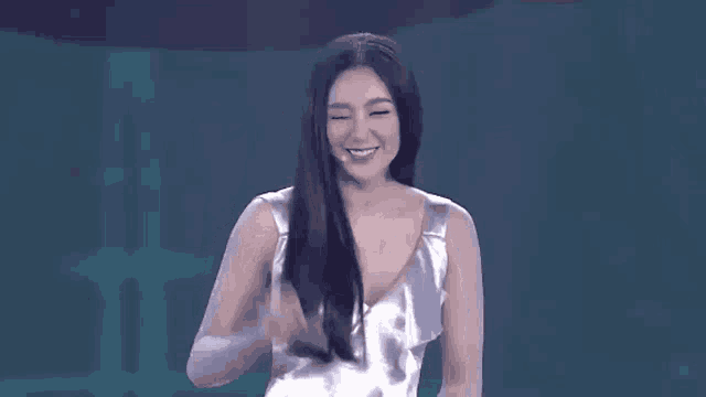 a woman in a silver dress is smiling while standing on a stage .