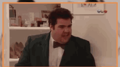 a man in a suit and bow tie is standing in front of a white board that says i love you .