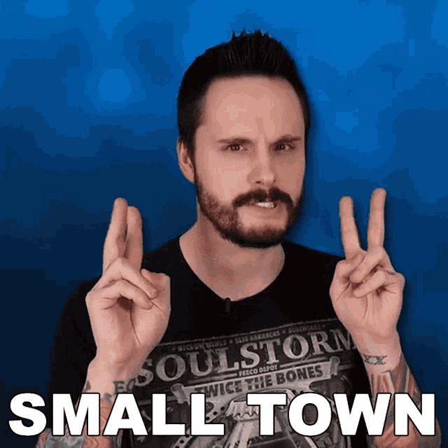 a man giving a peace sign with the words small town behind him