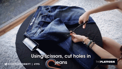 a person is cutting holes in a pair of jeans