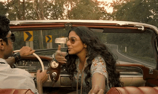 a man and a woman are driving down a road with arrows pointing to the left and right