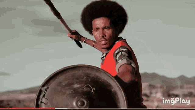 a man holding a spear and a shield with the words imgplay visible in the corner