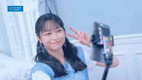 a girl taking a picture of herself with a blue sign that says up front world