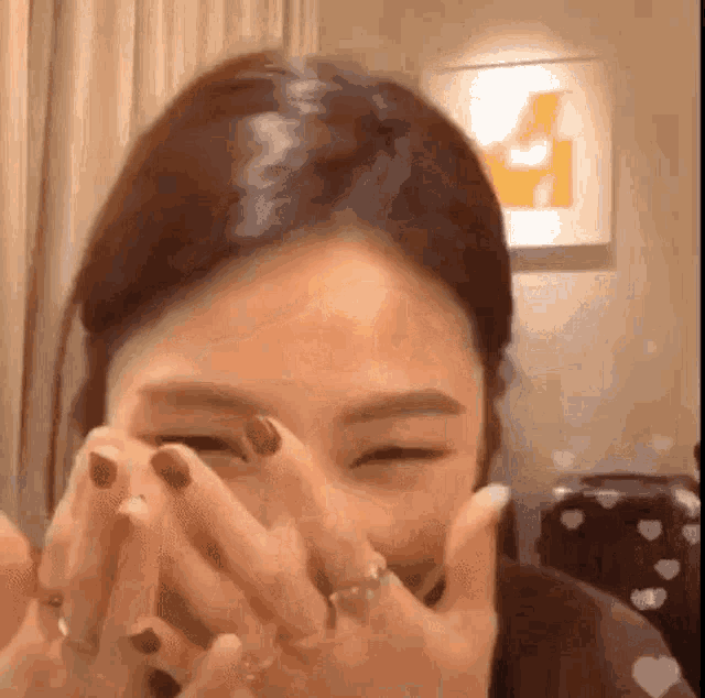 a woman is covering her face with her hands while wearing a ring .