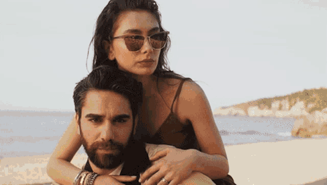 a woman wearing sunglasses sits on the back of a man