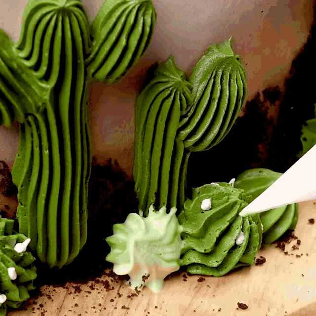 a cake decorated to look like a cactus is being frosted