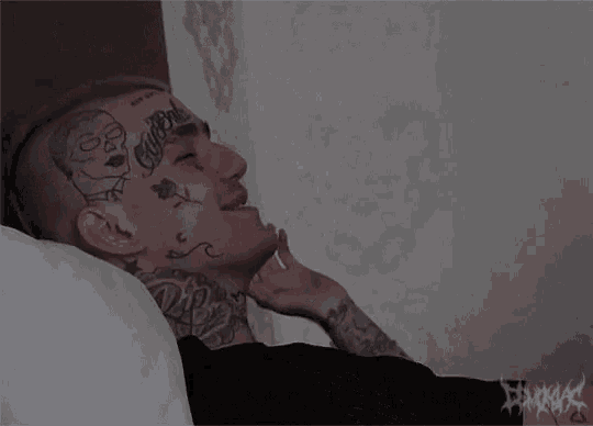 a man with a lot of tattoos on his face is laying down