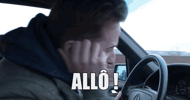 a man driving a car with the word allo written on the screen