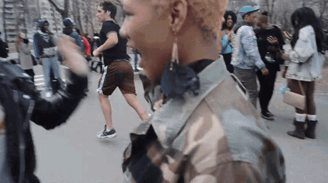 a woman in a camouflage jacket is standing in a crowd of people