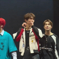 a group of young men are standing next to each other on a stage . one of the men has red hair .