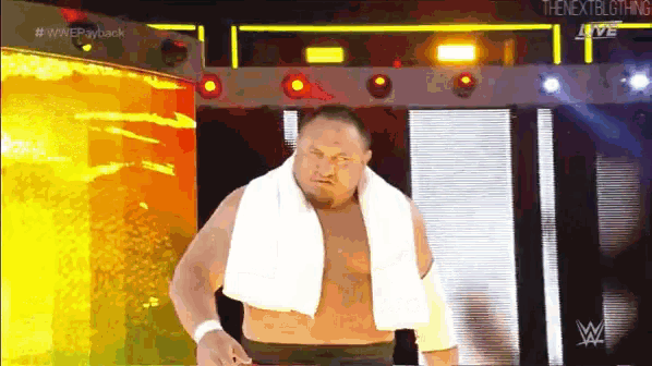 a wrestler with a white towel around his neck walks out of a tunnel .