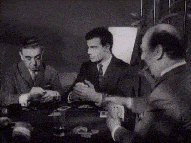 a group of men sitting around a table with cards on it