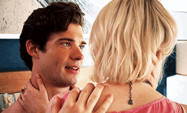 a man and a woman are looking at each other and the woman has a tattoo on her neck