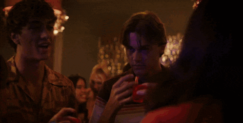 a group of young men are holding up red shot glasses