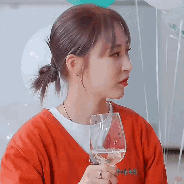 a woman in a red shirt holds a glass of water
