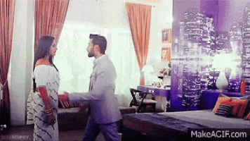 a man and a woman are standing in a room with a makeagif.com watermark on the bottom