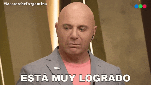 a bald man wearing a pink shirt and a gray jacket says esta muy logrado