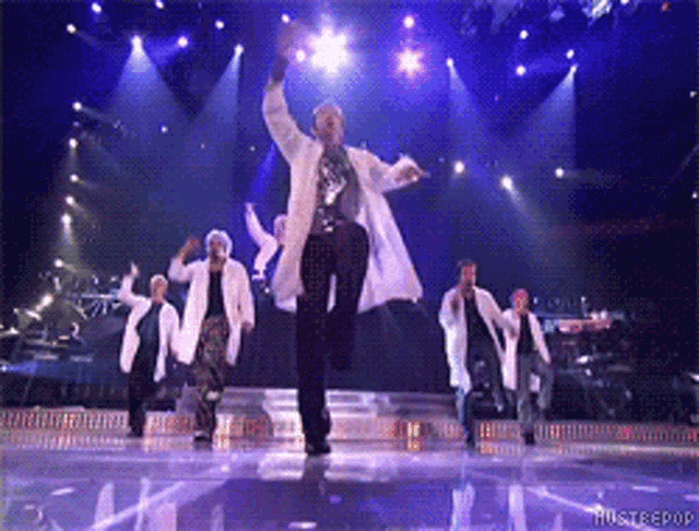 a group of people are dancing on a stage with the words hustlepop on the bottom right