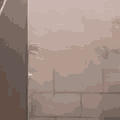 a man is peeking out from behind a door in a bathroom with chinese writing on the wall .