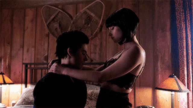 a man and a woman are hugging in a bedroom with snow boots on the wall