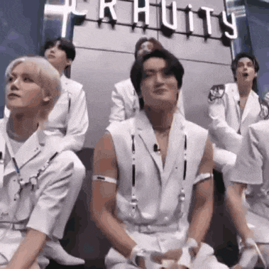 a group of men in white clothes are sitting on the floor .