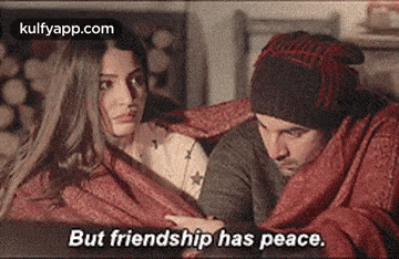 a man and a woman wrapped in a blanket are sitting next to each other .