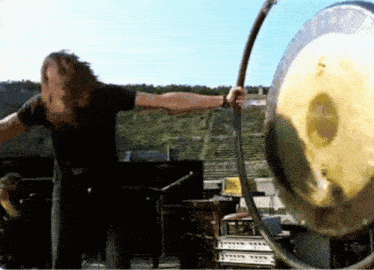 a man in a black shirt is playing a large gong