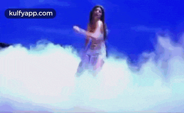 a woman in a white dress is standing in the clouds .