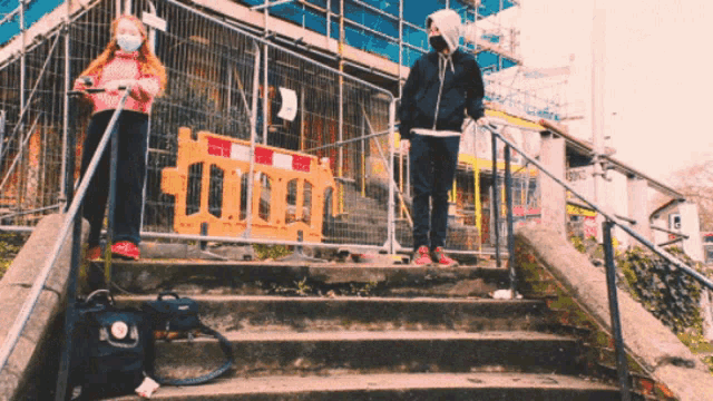 two people wearing masks are standing on a set of steps