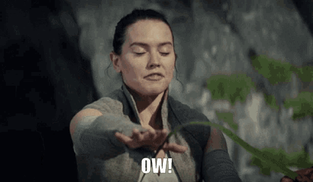 a woman is holding a plant in her hand and saying " ow "