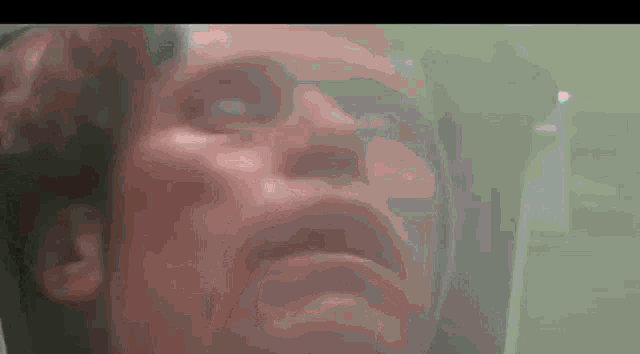 a close up of a man 's face in a green room
