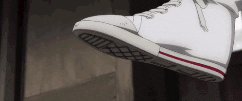 a close up of a person 's foot wearing a pair of white sneakers