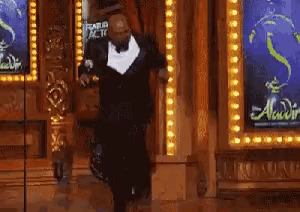 a man in a suit is dancing in front of a sign for aladdin