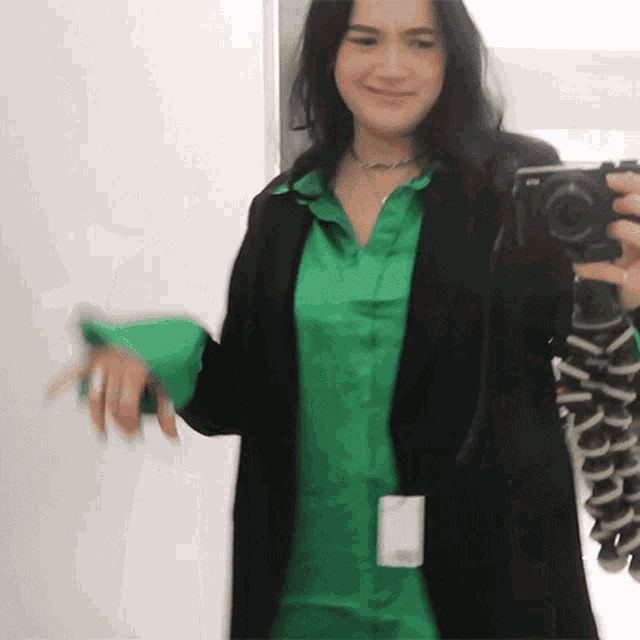 a woman in a green shirt is taking a selfie