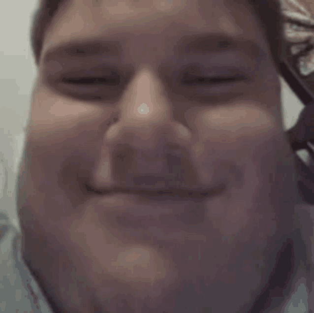 a close up of a man 's face with his eyes closed and a smile on his face .