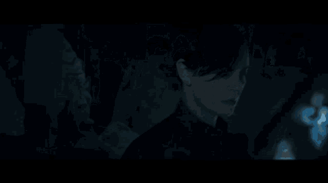 a man in a dark room with a stained glass window