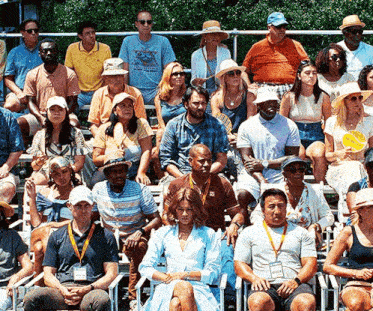a group of people sitting on bleachers with one man wearing a t-shirt that says ' i love you '