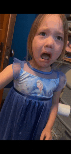 a little girl wearing a blue frozen dress making a funny face