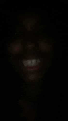 a close up of a person 's face in the dark with a smile on it .