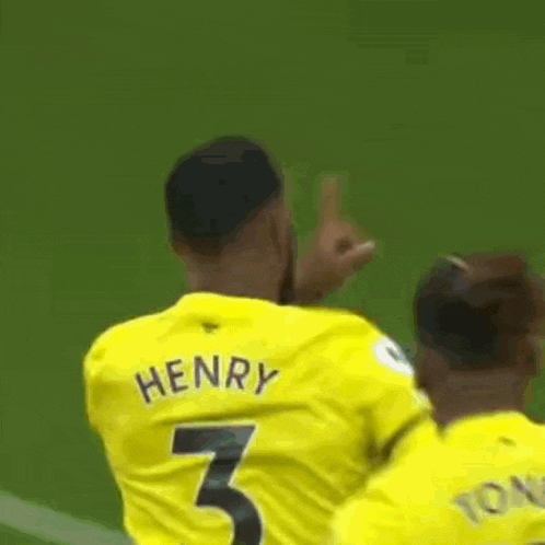 a soccer player in a yellow jersey is giving a thumbs up while another player looks on .