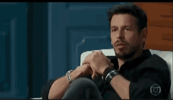 a man is sitting in a chair with his hands folded