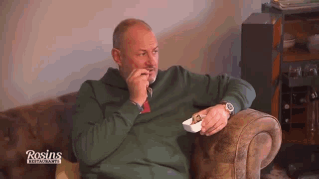 a man sitting on a couch with rosin 's restaurant written on the bottom