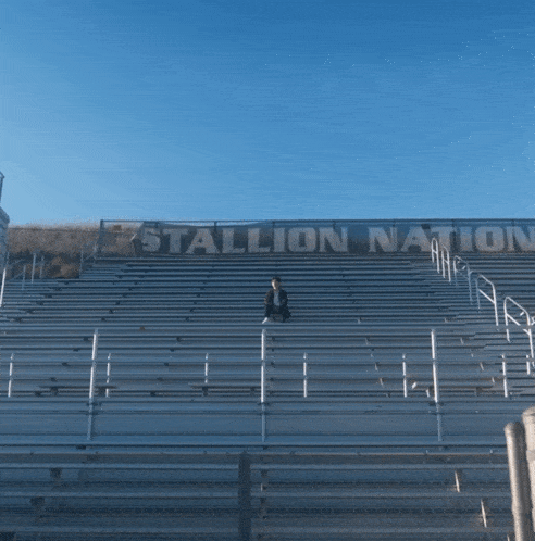 a man sits on the bleachers at the stallion nation
