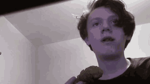 a young man is holding a piece of chicken in his hand