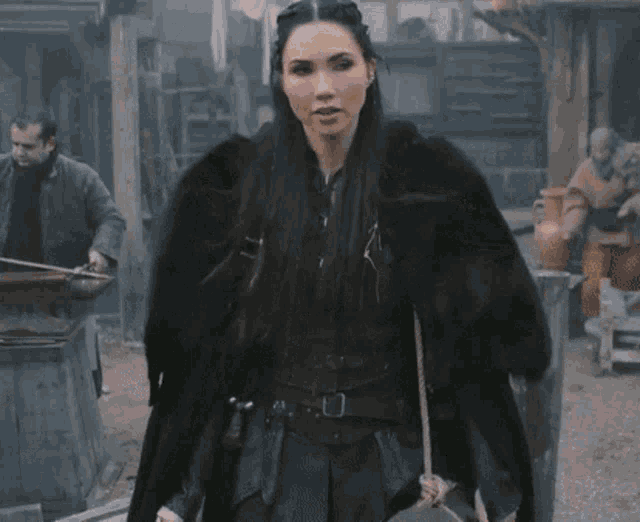 a woman in a fur coat stands in front of a group of men