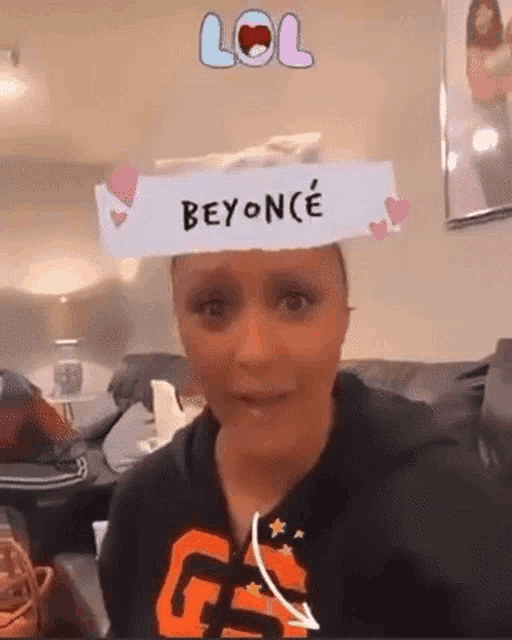 a woman is sitting on a couch with a beyonce filter on her head .