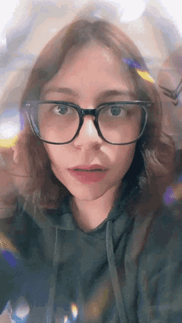 a young woman wearing glasses and a black hoodie