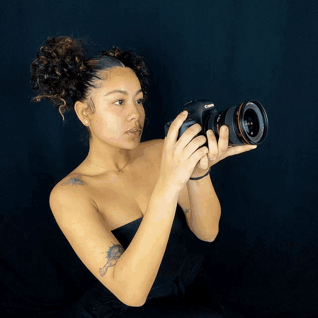 a woman holds a canon camera in her hands